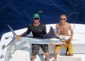 Pretty lit up white marlin being held by two anglers then released on an Ocracoke Gecko Sport Fishing Charters.